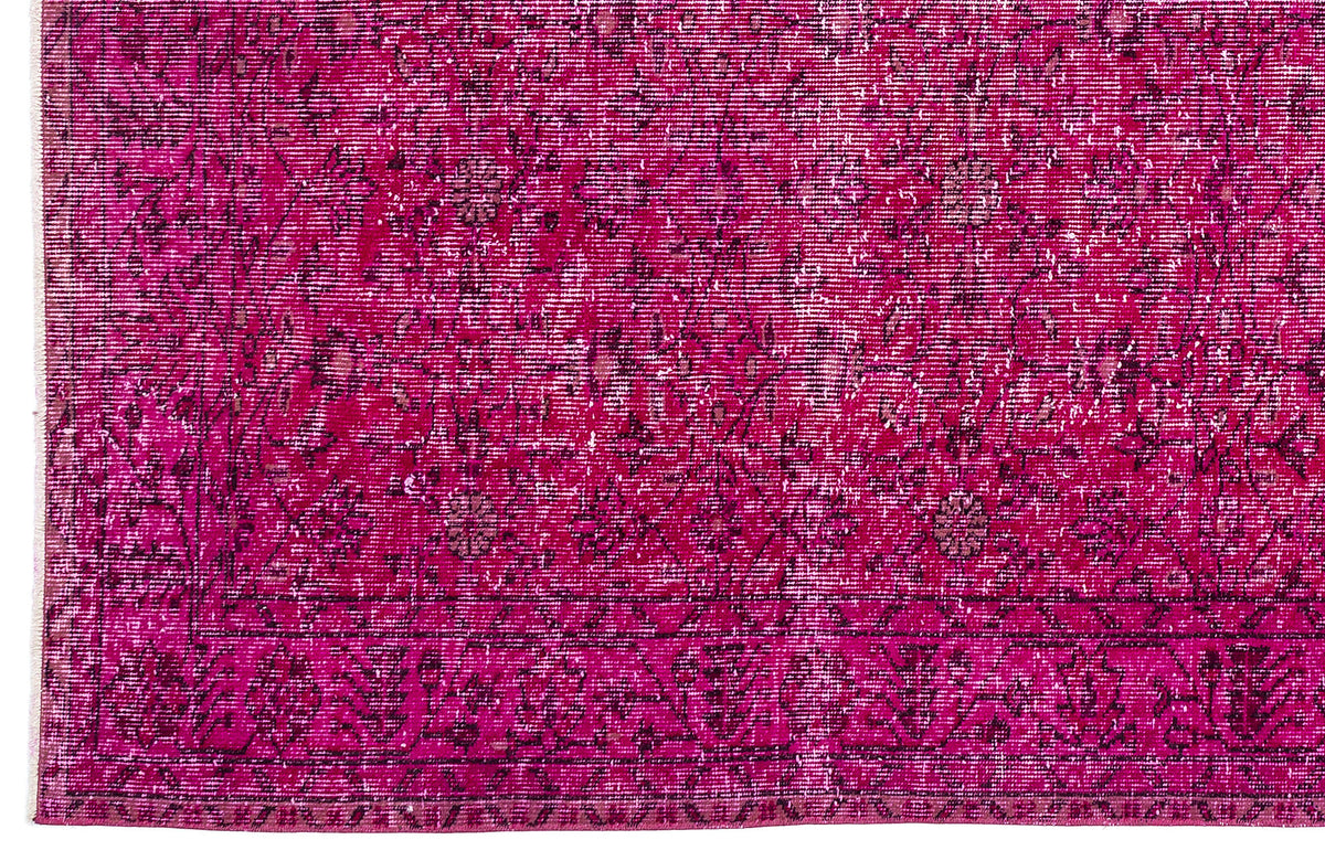 Magenta distressed rug with a dark floral medallion pattern and a geometric border.