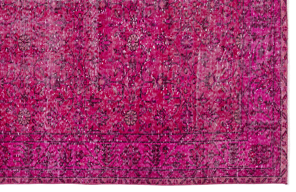 Magenta distressed rug with a traditional floral medallion pattern and a dark border.