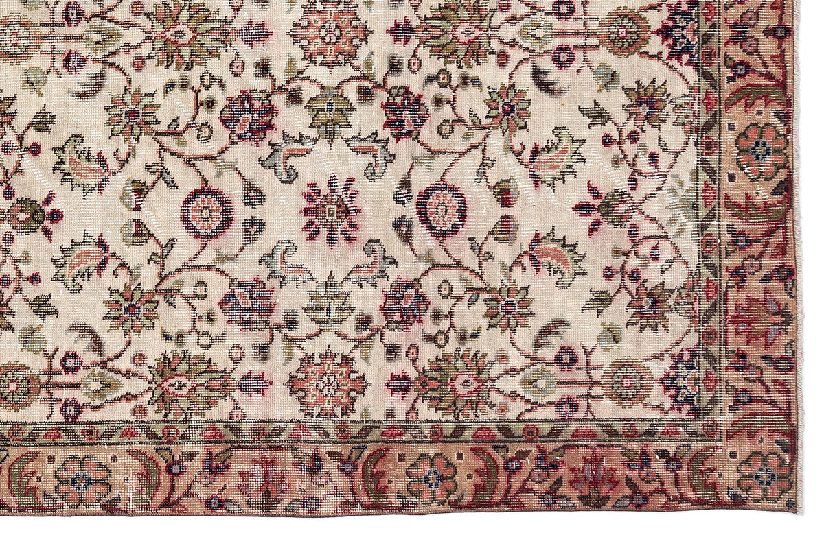 Beige traditional rug with a floral medallion pattern in muted red, green, and navy blue, featuring a decorative border.