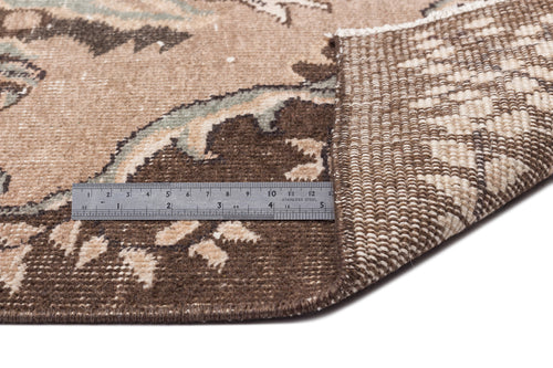 Load image 1 in gallery view. Brown and beige floral patterned rug with a folded corner showing the woven backing and a metal ruler for scale.