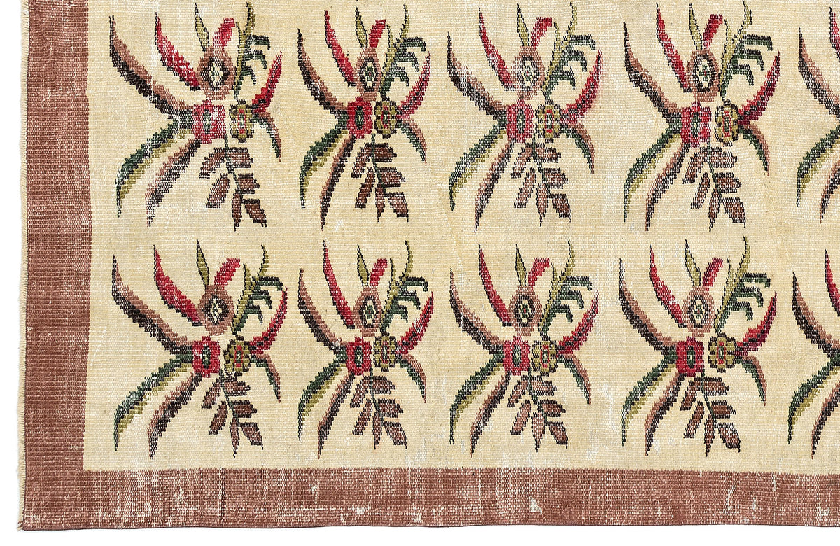 Cream rug with a repeating floral motif in red, green, and brown, featuring a solid brown border.