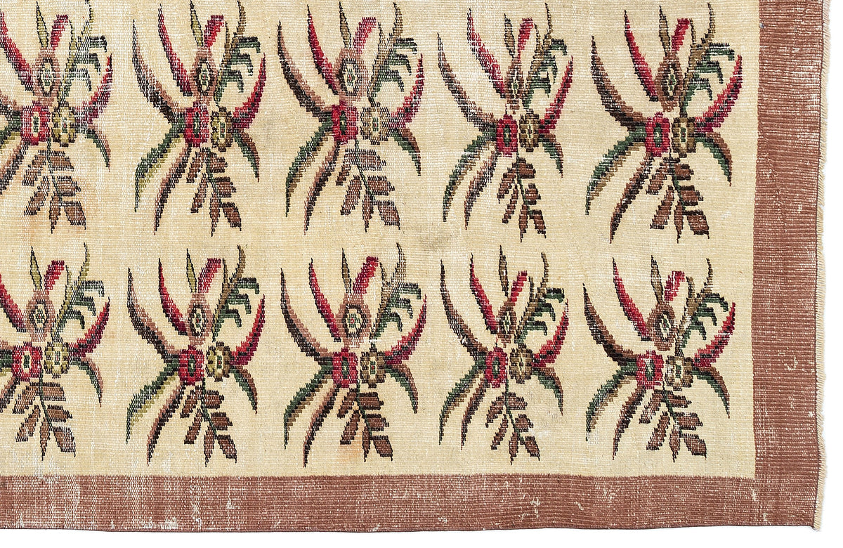 Cream rug with a repeating red, green, and brown floral motif and a solid brown border.