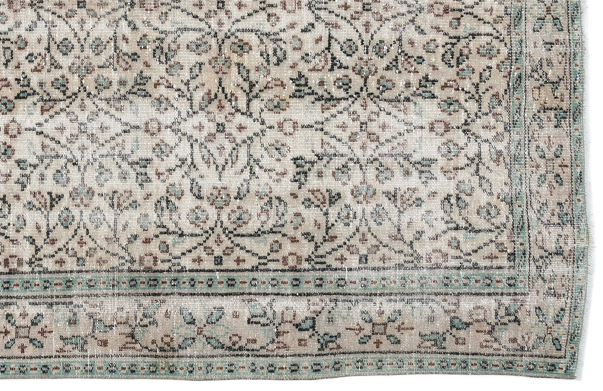 Beige vintage-style rug with a distressed floral pattern in muted teal and brown, featuring a decorative border.