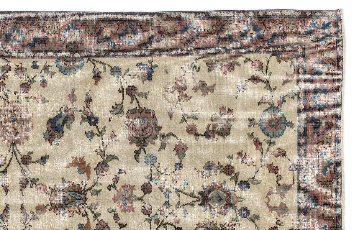 Beige rug with a faded floral vine pattern in muted blue and red, featuring a detailed decorative border.