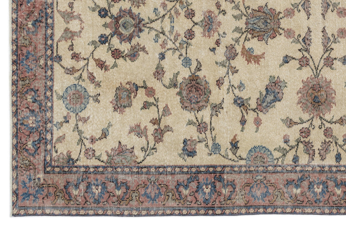 Beige rug with a distressed floral vine pattern in muted blue, red, and brown, featuring a decorative border.