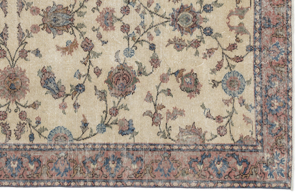Beige rug with a distressed floral vine pattern in muted blue, red, and green, featuring a decorative border.