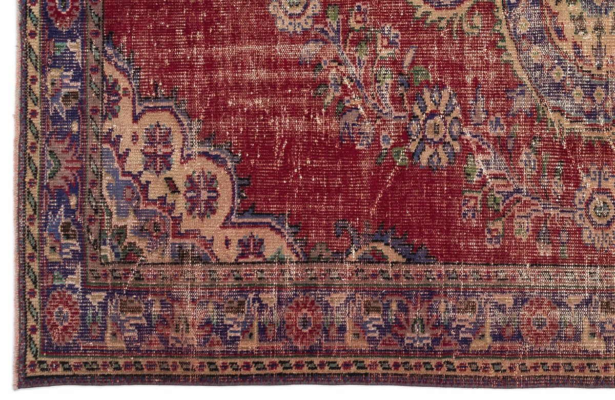 Distressed red traditional rug with blue and beige floral medallion patterns and a decorative border.