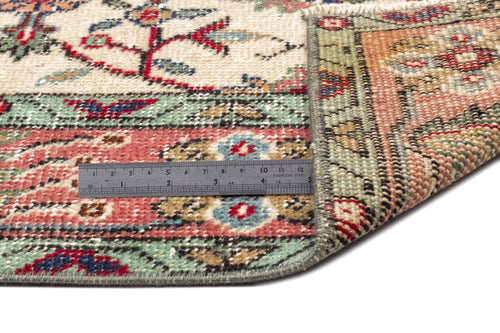 Load image 1 in gallery view. Multi-colored traditional rug with floral motifs and a geometric border, shown folded with a metal ruler for scale.