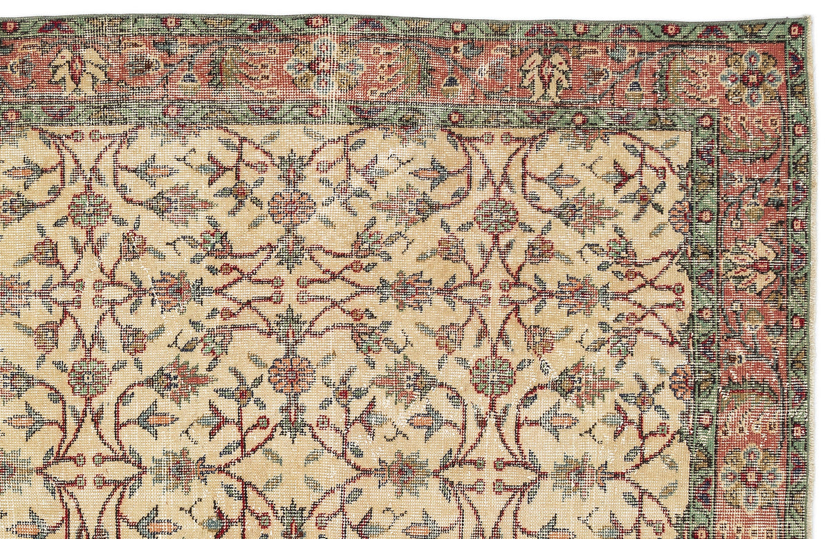 Beige traditional rug with a red and green floral vine border and a repeating botanical pattern in the center.