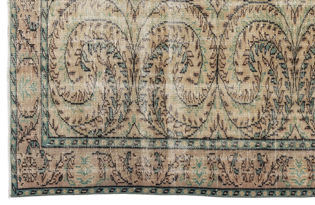 Distressed beige and teal rug with a traditional botanical paisley pattern and a geometric border.