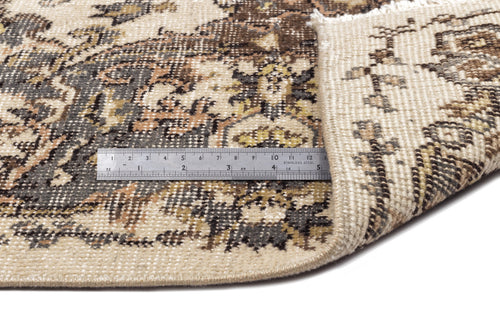 Load image 1 in gallery view. Beige, brown, and charcoal traditional medallion rug with a folded corner and a metal ruler for scale.