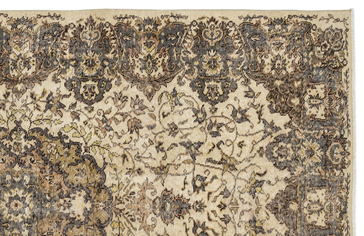 Distressed beige and charcoal rug with a traditional floral medallion border and intricate vine pattern.