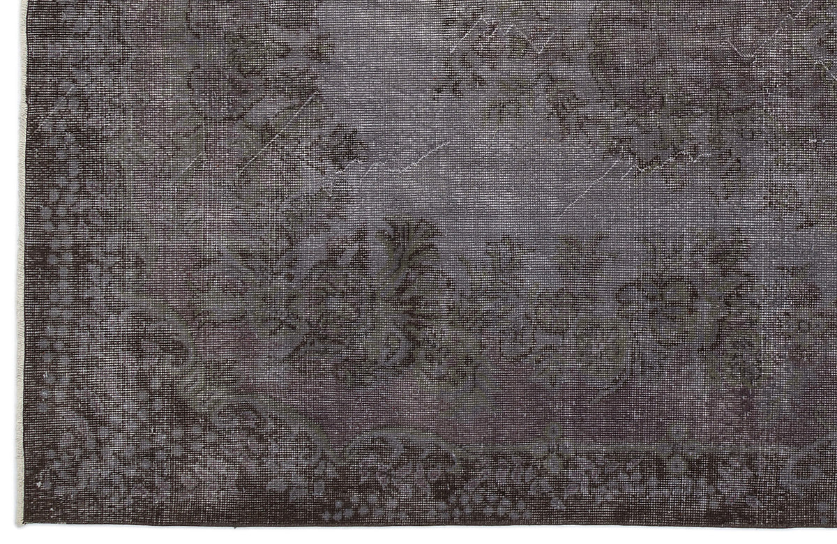 Charcoal grey rug with a faded, traditional floral medallion pattern and a decorative border.