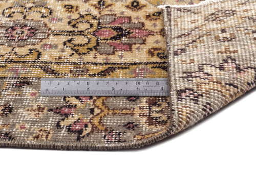 Load image 1 in gallery view. Distressed floral medallion rug in gold, grey, and pink with a metal ruler showing pile height on a white background.
