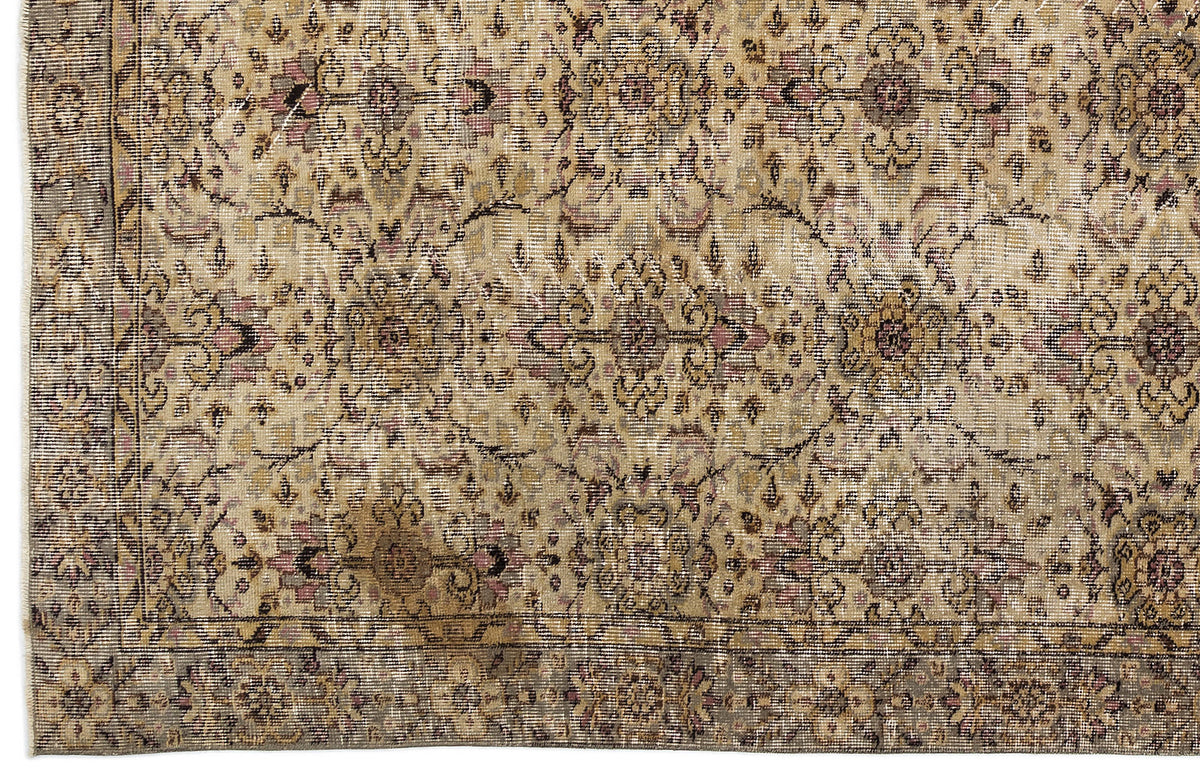 Distressed beige and tan rug with a faded floral medallion pattern and a dark border.