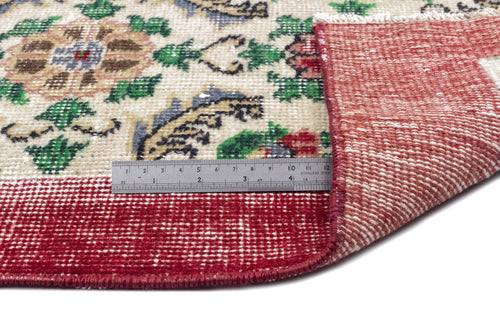 Load image 1 in gallery view. Cream rug with a floral medallion pattern in red, green, and blue, shown folded to reveal the red backing and a ruler.