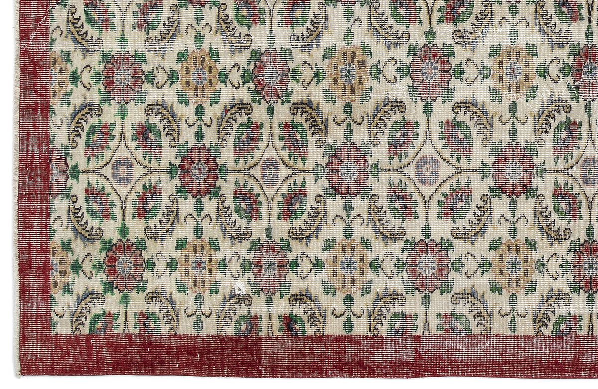 Cream rug with a red border and a repeating floral medallion pattern in red, green, and gold.