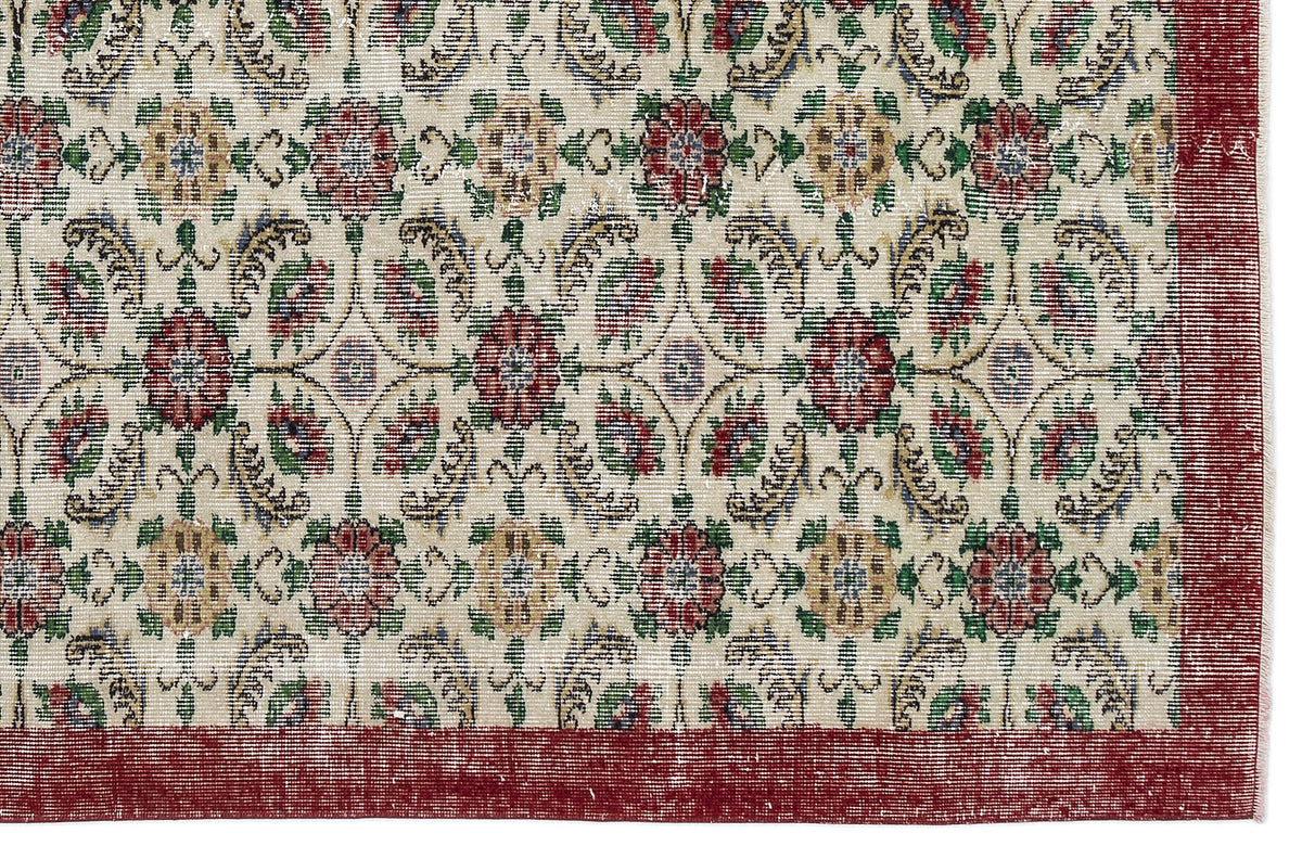 Cream rug with a repeating floral medallion pattern in red, green, and gold, featuring a wide solid red border.