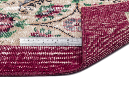 Load image 1 in gallery view. Beige and burgundy floral rug with a folded corner showing the woven backing and a metal ruler for scale.