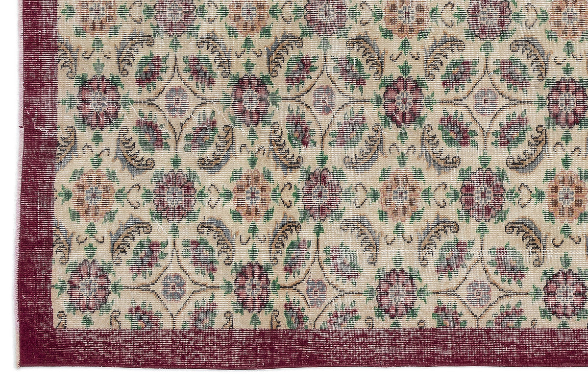 Beige rug with a maroon border and a repeating floral medallion pattern in maroon, green, and muted blue.
