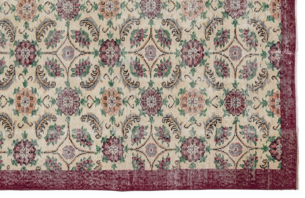 Beige rug with a repeating floral medallion pattern in burgundy, green, and blue, featuring a solid burgundy border.