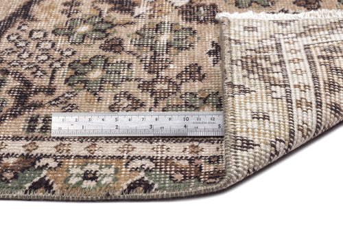 Load image 1 in gallery view. Beige, brown, and green floral patterned rug with a folded corner showing the woven backing and a metal ruler for scale.