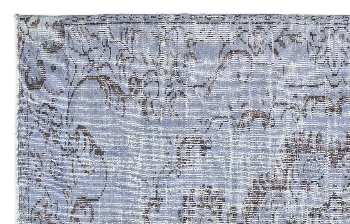 Periwinkle and charcoal rug with a distressed, faded traditional floral medallion pattern.