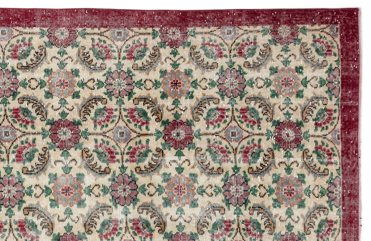 Beige rug with a red border and a repeating floral medallion pattern in red, green, and blue on a white background.