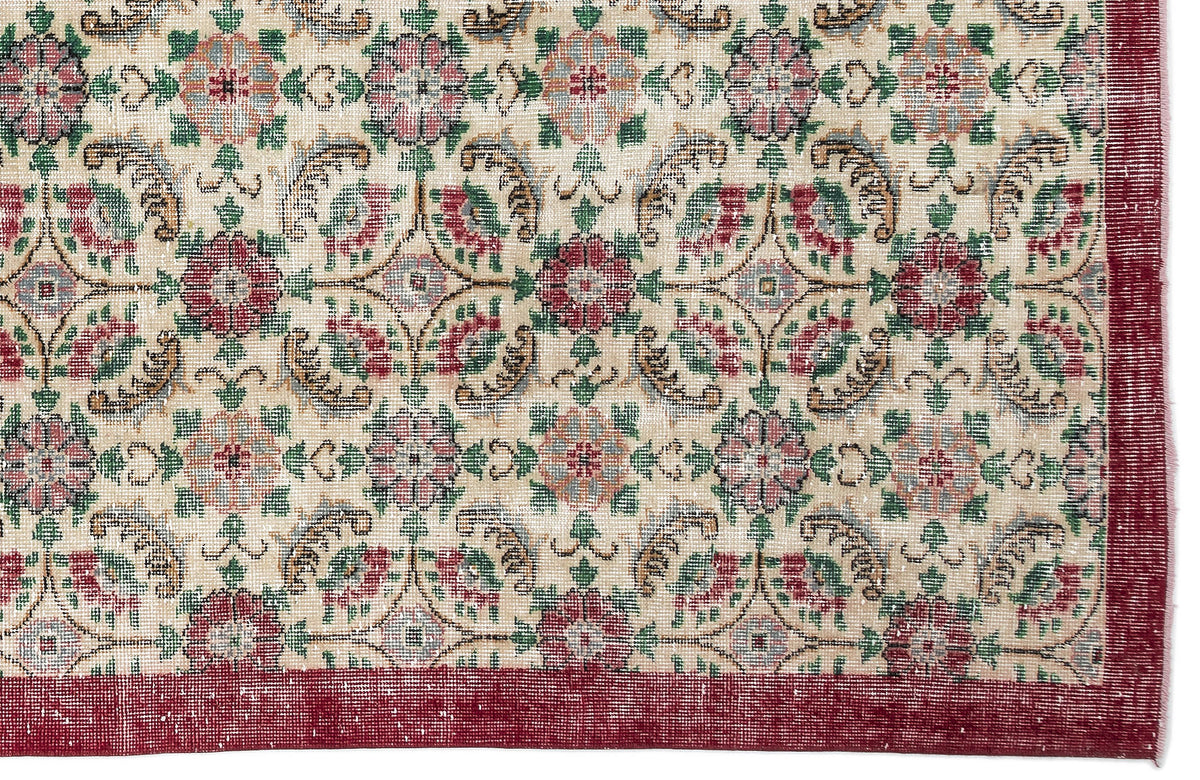 Beige rug with a repeating floral medallion pattern in red, green, and blue, featuring a solid red border.