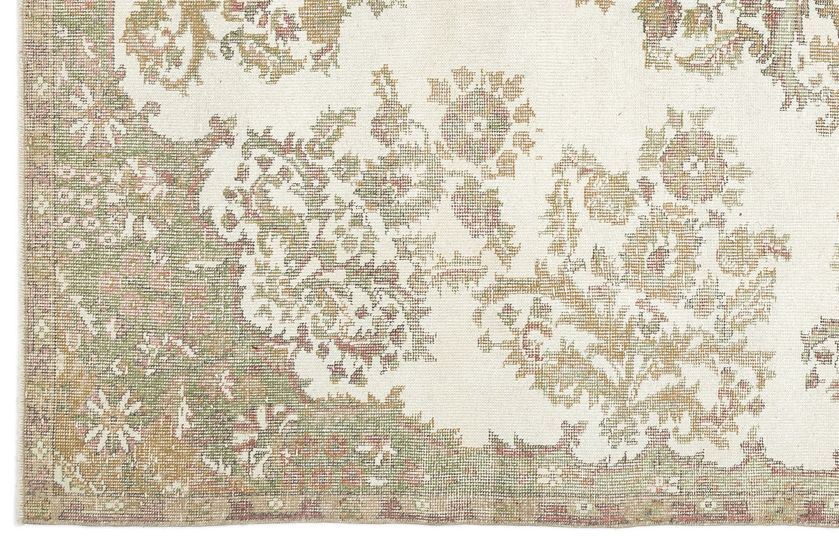 A close-up of the Bofaya - Vintage Medallion Rug (6'4" x 10'2") highlights its ornate floral pattern in muted green, beige, and brown tones, complete with a decorative border.