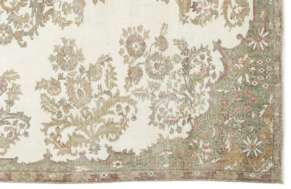 A close-up of the Bofaya Vintage Medallion Rug (6'4" x 10'2"), showcasing a cream background with intricate floral and vine motifs in muted green, gold, and brown, plus a decorative border along the right and lower edges.