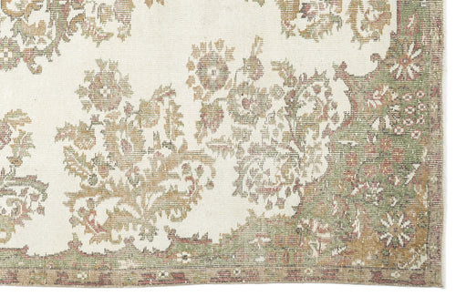 Load image 1 in gallery view. A close-up of the Bofaya Vintage Medallion Rug (6'4" x 10'2"), showcasing a cream background with intricate floral and vine motifs in muted green, gold, and brown, plus a decorative border along the right and lower edges.
