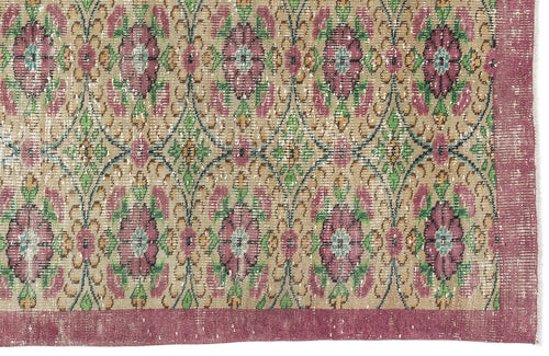Load image 1 in gallery view. Distressed beige rug with a repeating floral medallion pattern in magenta, green, and teal, featuring a wide magenta border.