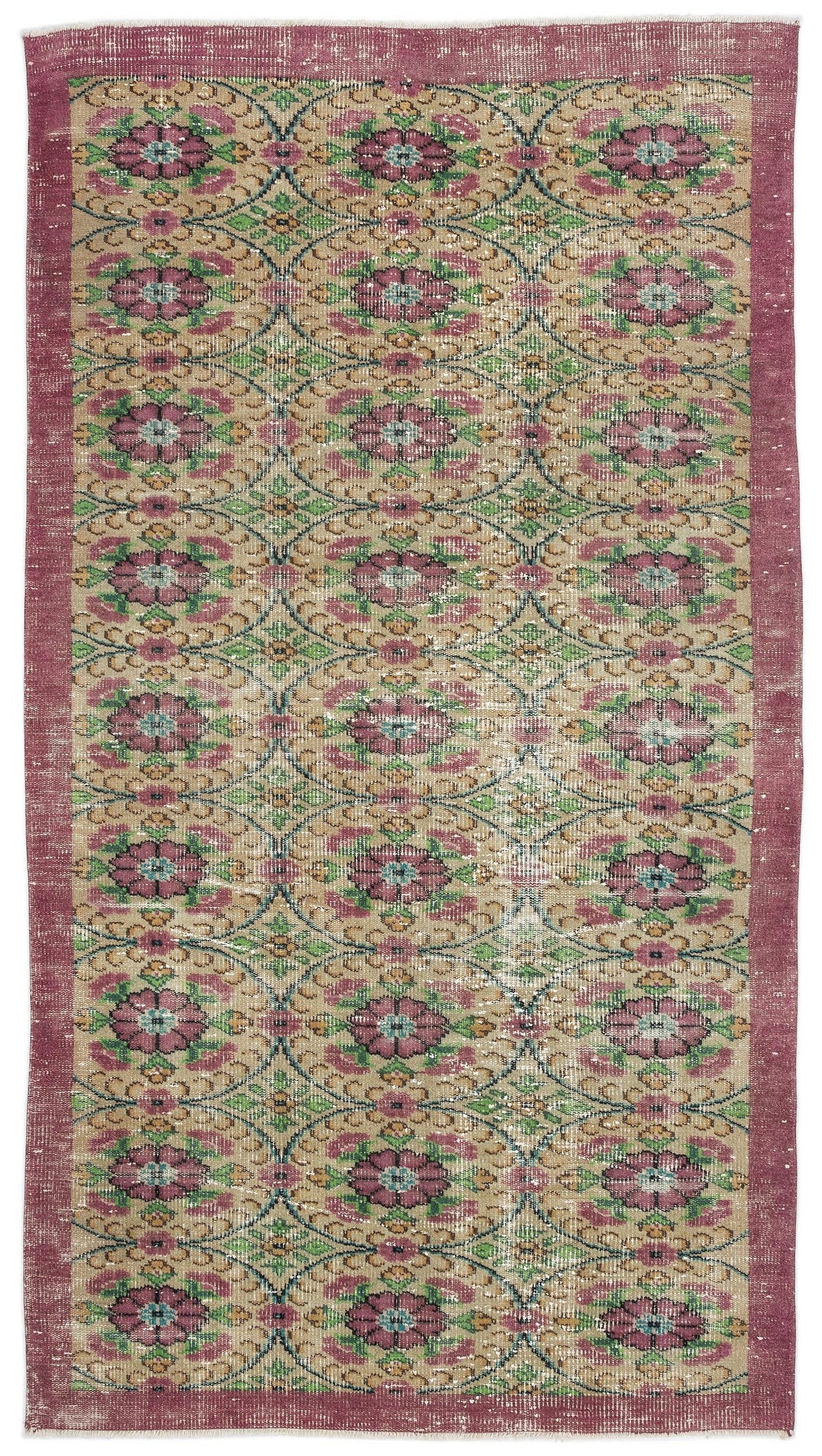 Distressed tan rug with a repeating floral medallion pattern in pink, green, and blue, framed by a solid pink border.