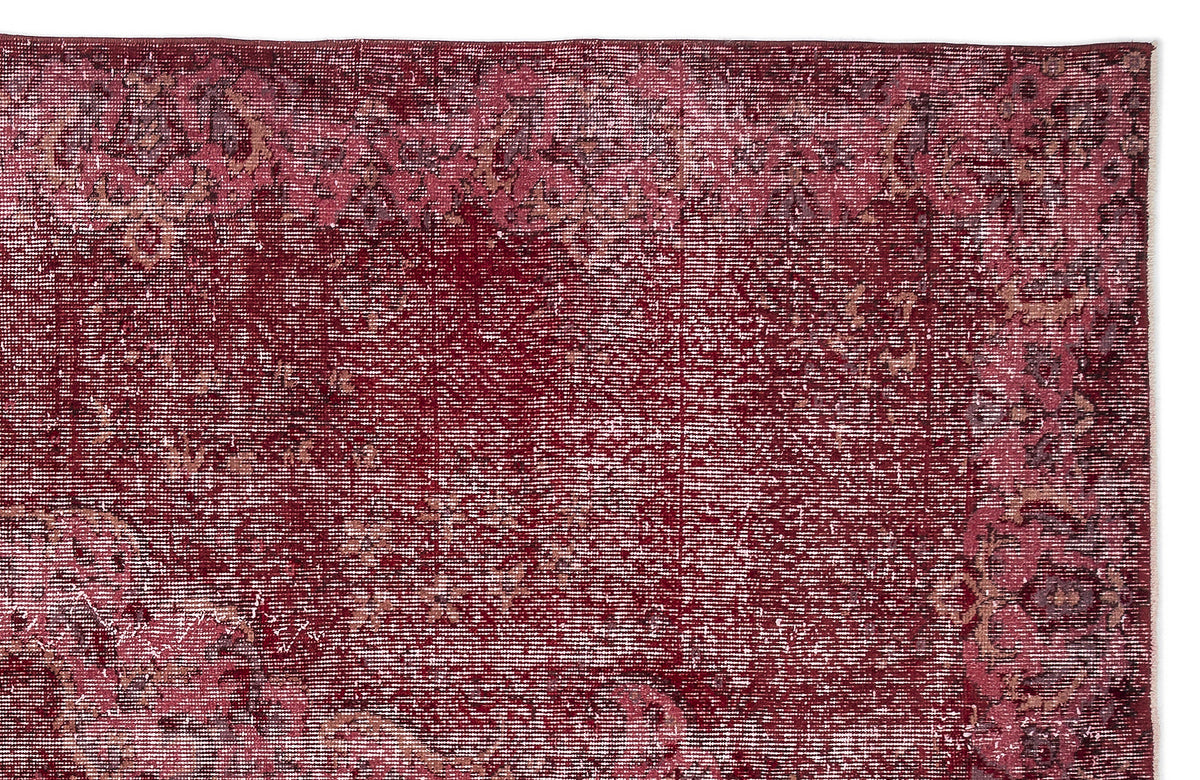 Deep red distressed rug with a faded traditional floral medallion pattern.