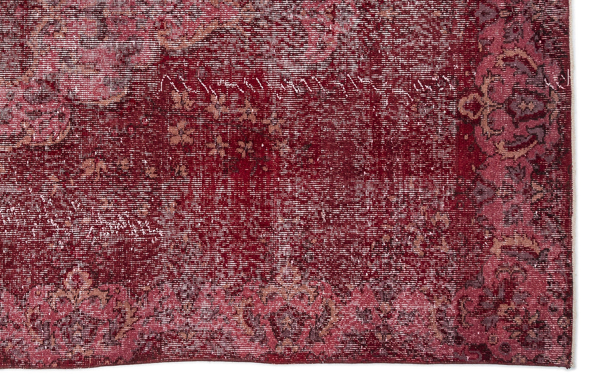 Deep red distressed rug with a faded floral medallion pattern and a decorative border.