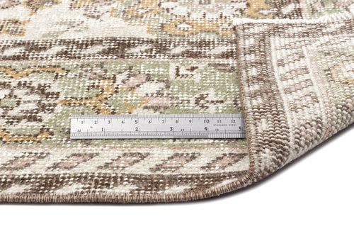 Load image 1 in gallery view. A close-up of the Nizora - Vintage Floral Rug (6'1 x 10'0) shows a metal ruler in inches and centimeters on top, with one corner folded to display the underside.