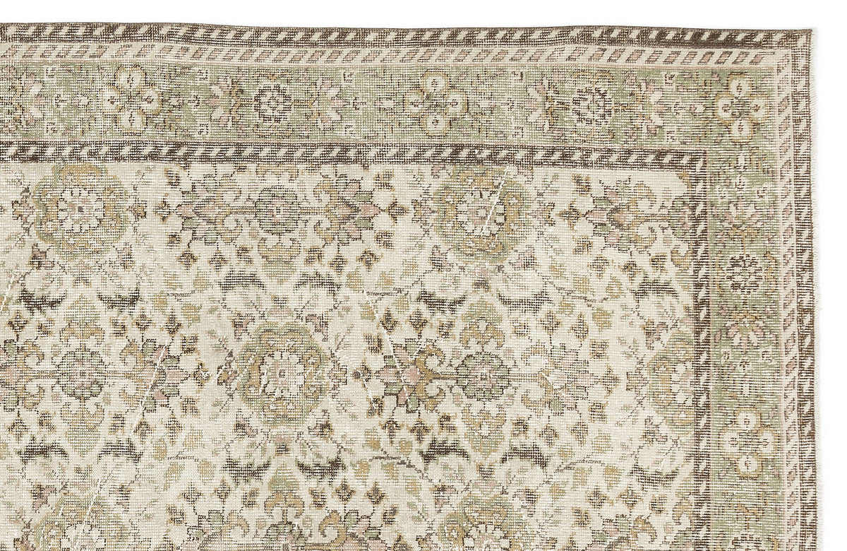 The Nizora - Vintage Floral Rug (6'1 x 10'0) features an intricate mix of floral and geometric patterns in muted beige, green, and brown tones, with a decorative border along the top and right edges.