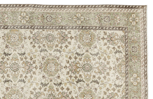 Load image 1 in gallery view. The Nizora - Vintage Floral Rug (6'1 x 10'0) features an intricate mix of floral and geometric patterns in muted beige, green, and brown tones, with a decorative border along the top and right edges.