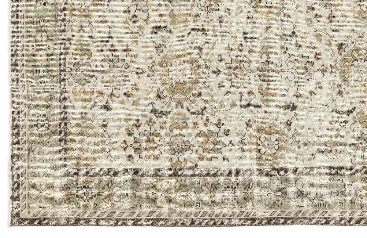 A close-up of the Nizora - Vintage Floral Rug (6'1 x 10'0) shows its beige background with floral and geometric patterns in muted green, brown, and gold tones, framed by a decorative border.