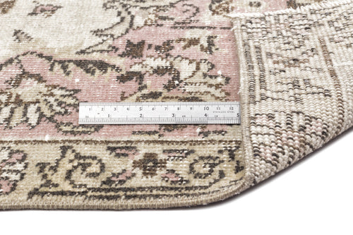 Load image 1 in gallery view. Distressed pink, beige, and brown vintage-style rug with a floral medallion pattern, showing the woven backing and a ruler.