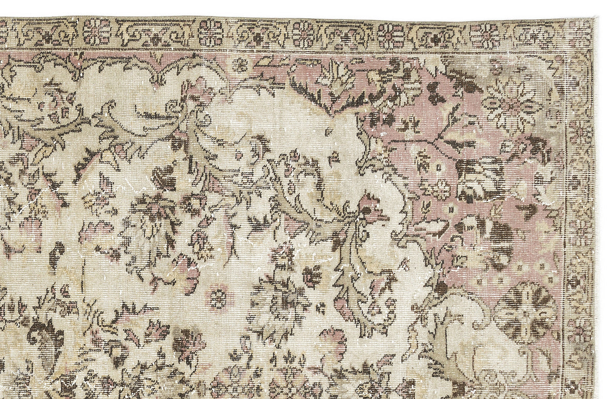 Distressed vintage-style rug with a faded floral medallion pattern in muted pink, beige, and brown tones.
