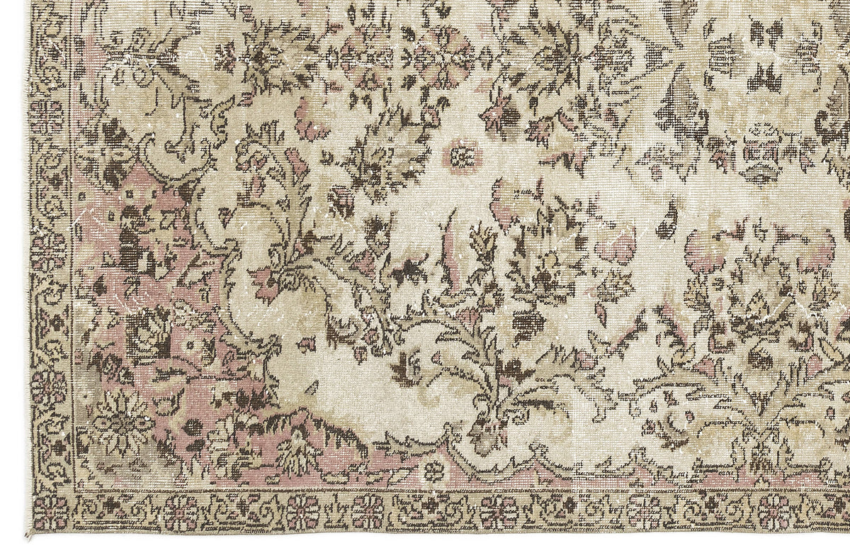 Distressed beige rug with a faded floral medallion pattern in muted pink and dark brown.