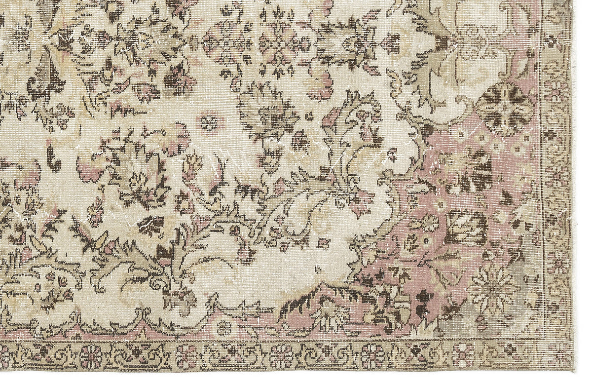 Distressed beige, brown, and dusty pink rug with a traditional floral medallion pattern and a detailed border.