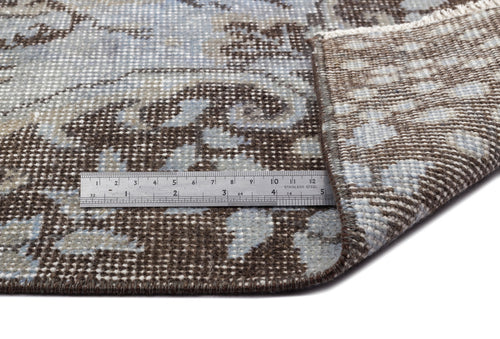 Load image 1 in gallery view. Brown and light blue floral medallion rug with a folded corner and a metal ruler for scale.