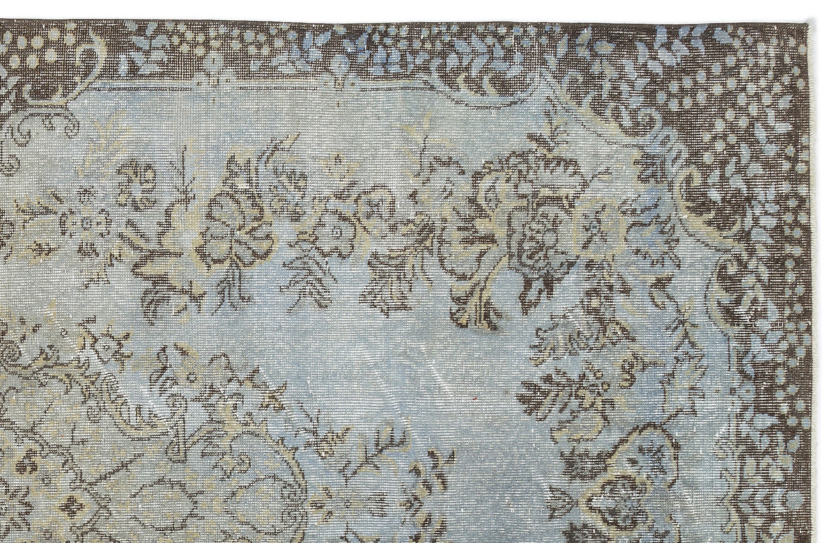 Distressed light blue and brown rug with a traditional floral medallion pattern and ornate border.