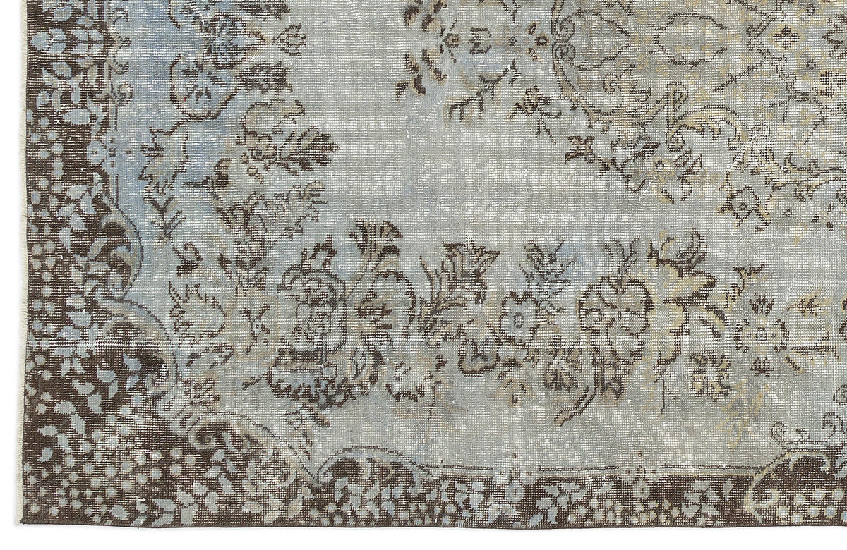 Light blue and brown rug with a distressed floral medallion pattern and a dark border.