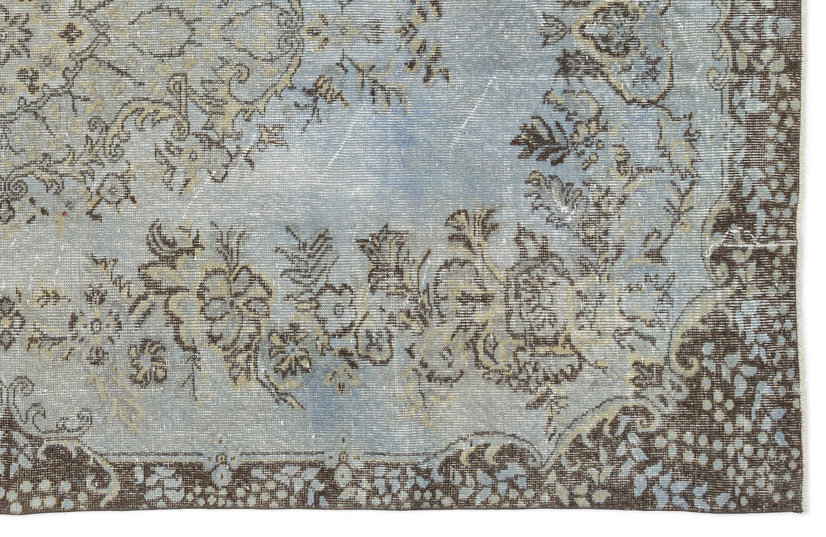 Light blue and brown distressed rug with a traditional floral medallion pattern and ornate border.