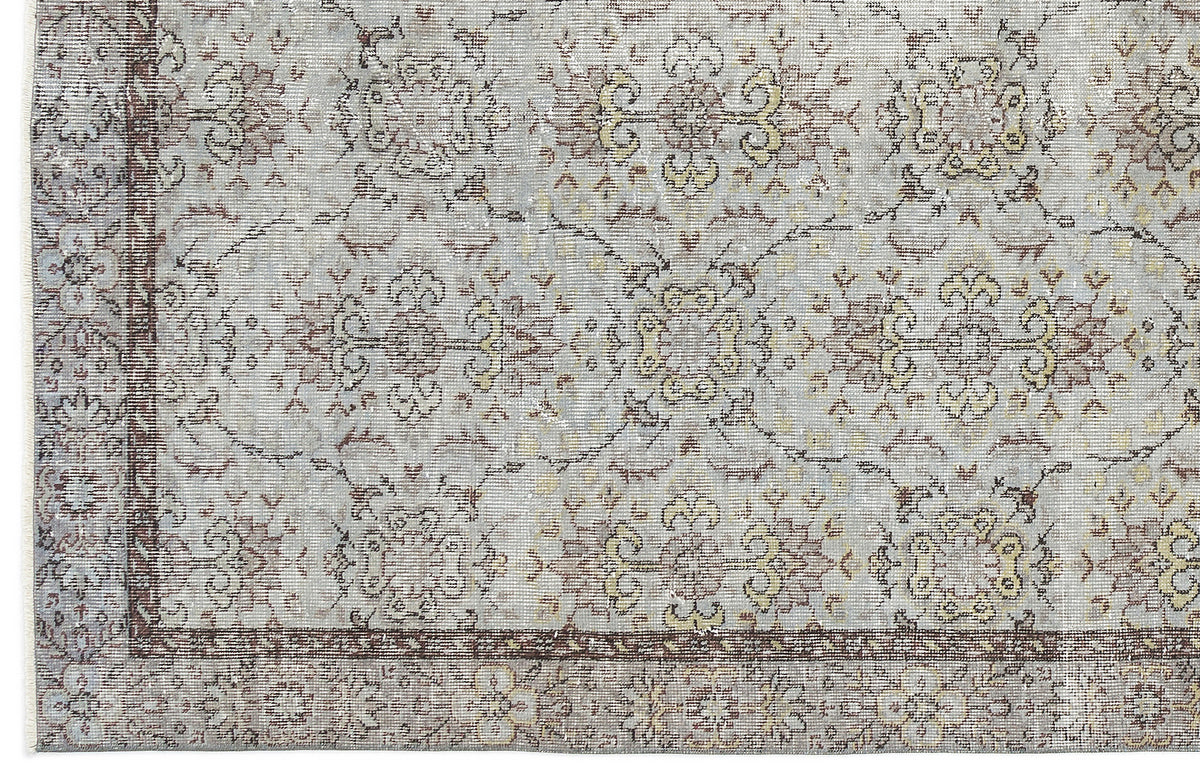 Light gray rug with a distressed traditional floral medallion pattern in muted brown and yellow tones.