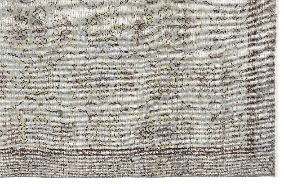 Light gray rug with a distressed floral medallion pattern in muted brown and yellow, featuring a dark border.